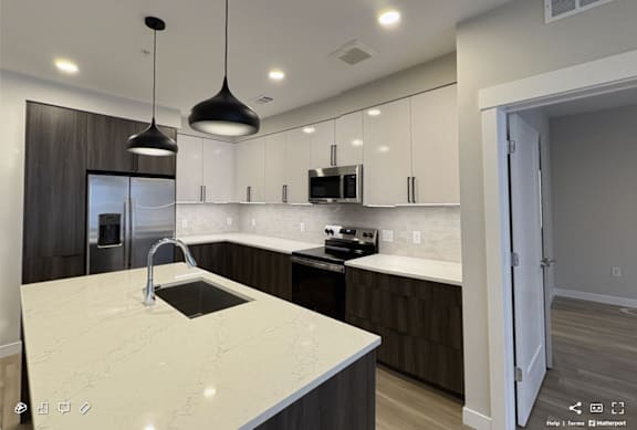 A modern kitchen with a white marble countertop and dark wood cabinets.