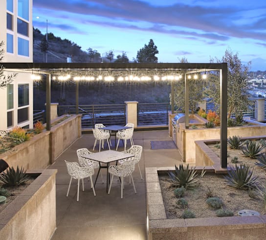 A patio with a table and chairs is lit up with string lights.