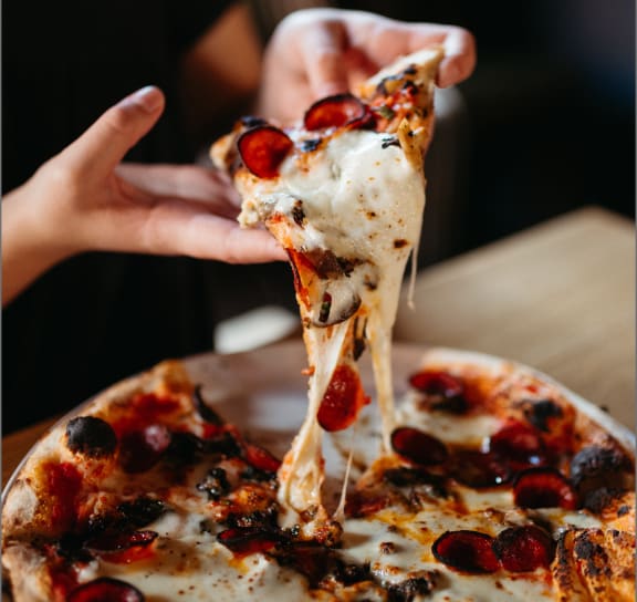 Woman Holding Slice of Cheesy Pizza