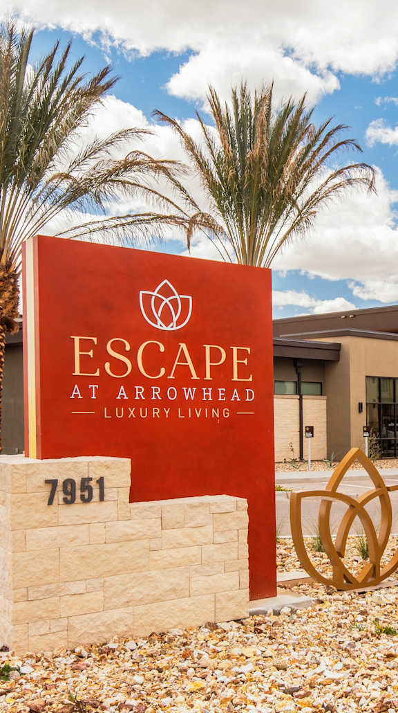 A sign for Escape at Arrowhead stands in front of a building.