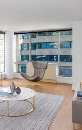 A modern living room with a grey sofa, a coffee table, and a large window.