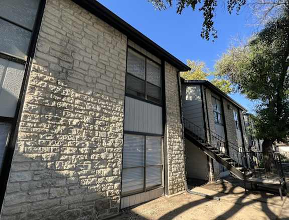 A building with a stone wall and a metal staircase.