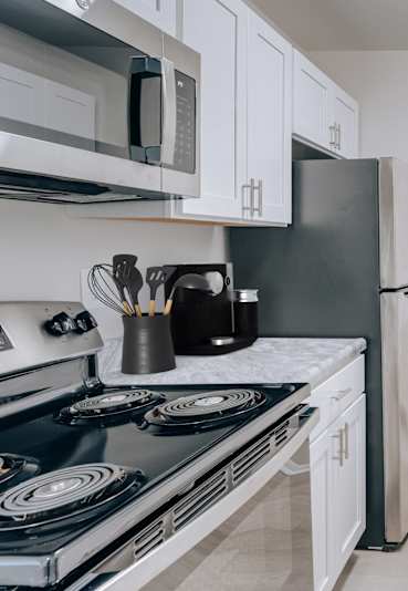 A kitchen with a black stove top oven and white cabinets.