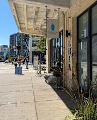 A blue bottle coffee shop with people sitting outside.