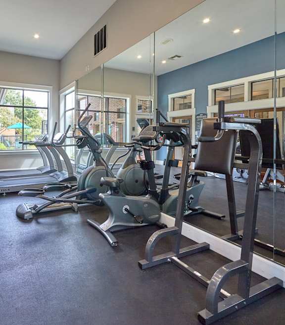 The fitness center at Fusion Crossroads Apartments with cardio equipment and large windows.