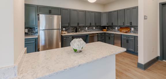 A kitchen with a marble countertop and a stainless steel refrigerator.