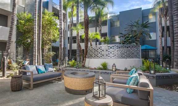 A patio area with wicker furniture and a stone wall.