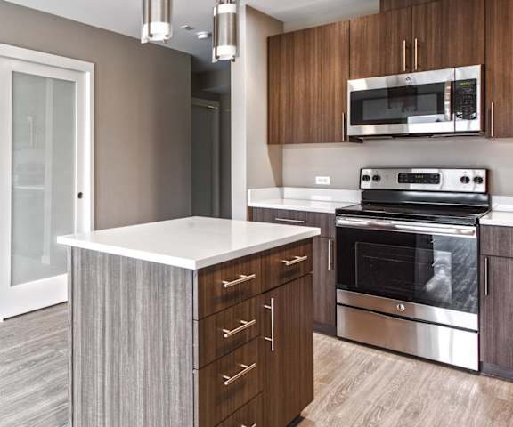 A modern kitchen with a white countertop and stainless steel appliances.