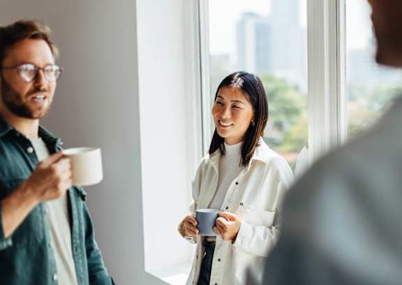 A man and a woman are having a conversation in a bright room with a city view.