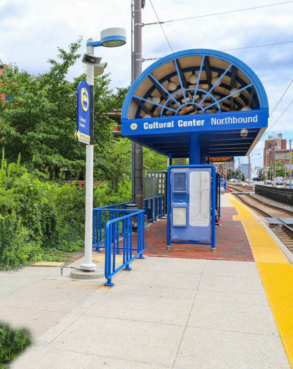 a blue train station with trees and bushes in the background at Symphony Center Apartments, Baltimore, MD, 21201
