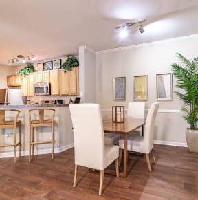 a dining area with a table and chairs and a kitchen in the background