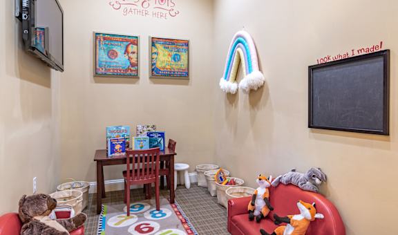 a childs play area with toys and a chalkboard on the wall
