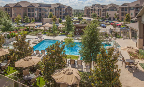an aerial view of the resort style pool with lounge chairs and umbrellas at Ovation at Lewisville Apartments, Texas , 75067