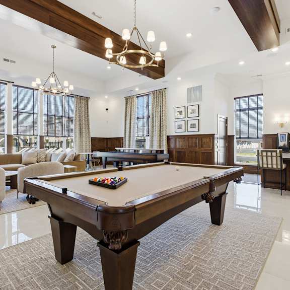 A large billiard table is in the middle of a spacious room with a pool table and a couch.