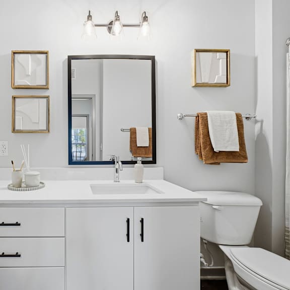 A white bathroom with a sink, mirror, and toilet.