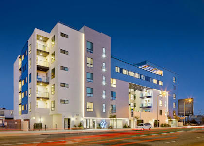 A modern multi-story building with a white facade and blue accents.