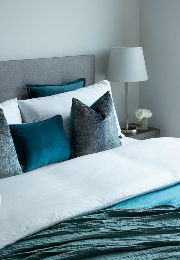 a bed with blue and white pillows and a grey headboard