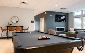 A pool table is in the middle of a room with a TV and a couch.