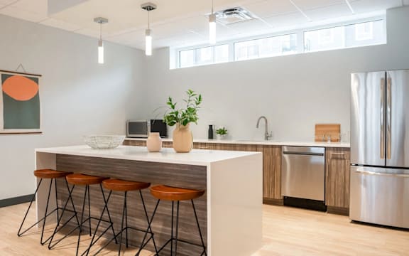 A kitchen with a white counter and orange bar stools.at Latitude 49 Townhomes, Winnipeg Manitoba