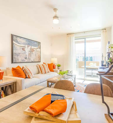 A living room with a white couch and orange pillows.