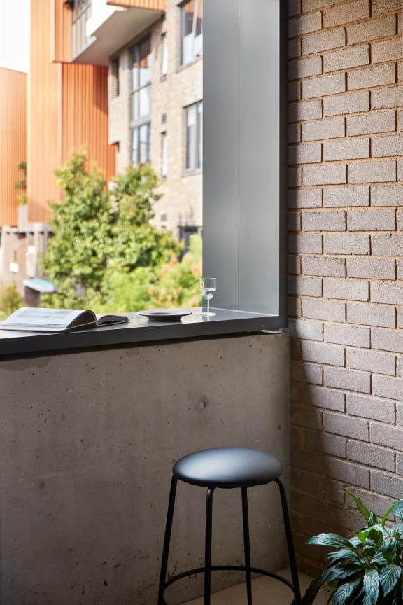 a stool in front of a window on a brick wall