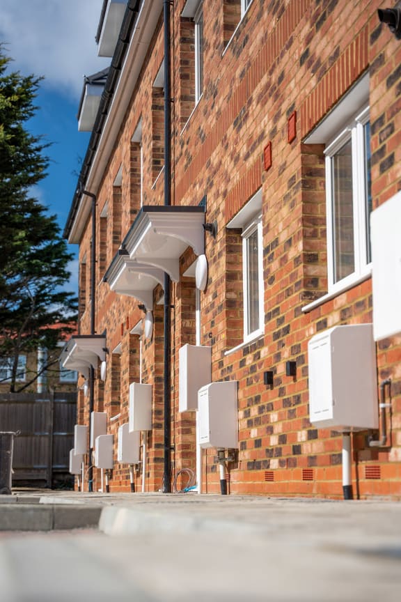 a row of air conditioning units on the side of a brick building