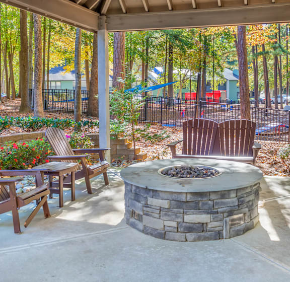 A patio with a fire pit and chairs.
