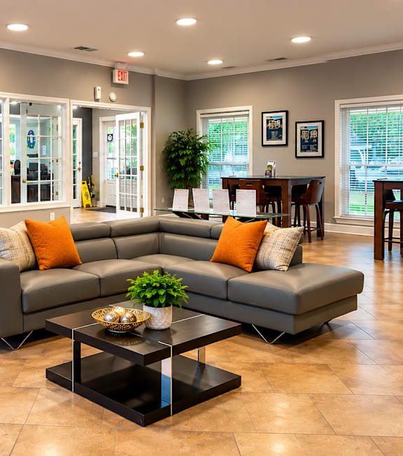 A spacious living room with a grey sofa, orange chairs, and a coffee table.