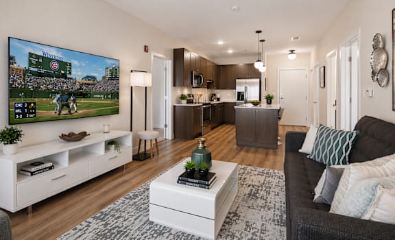 Modern apartment living room with open kitchen layout and TV showing a Chicago Cubs game at Panton Mill Apartments