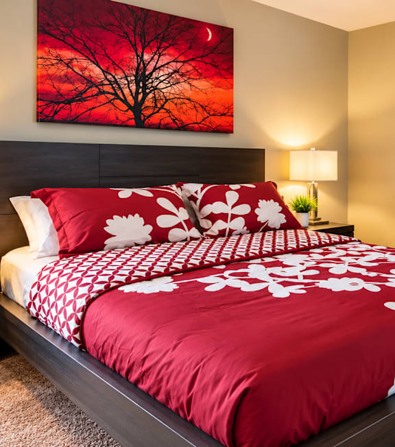 A bedroom with a red and white bedspread and two lamps on either side of the bed.