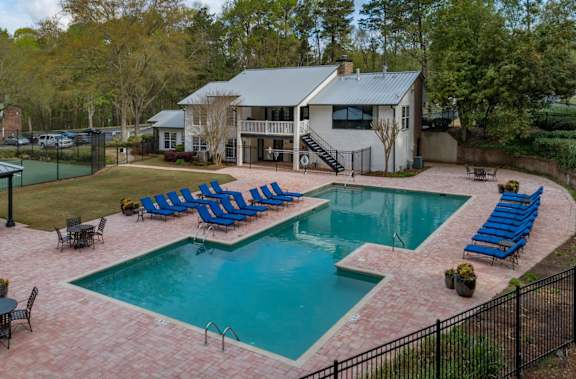 a swimming pool with chaise lounge chairs and a house in the background