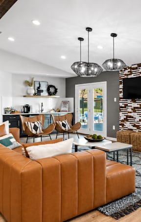 A living room with a brown sofa and a stone wall.