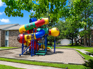 A colorful playground structure with a slide in the middle of a grassy area.