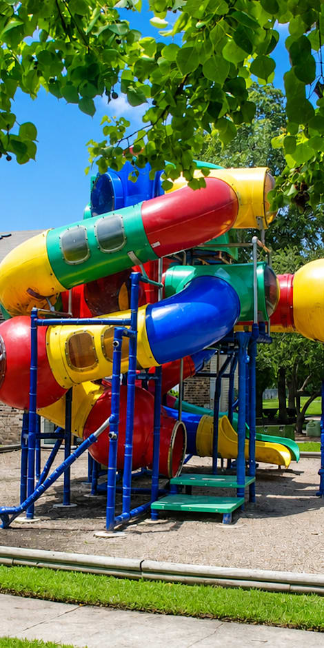 A colorful playground structure with a slide in the middle of a grassy area.