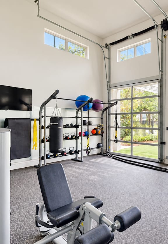 A home gym with a television, weights, and exercise equipment.