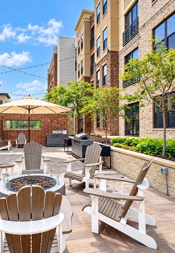 A patio with chairs and a fire pit in the middle of a courtyard.