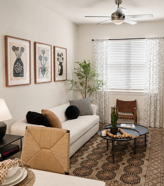 A living room with a white couch, a coffee table, and a ceiling fan.
