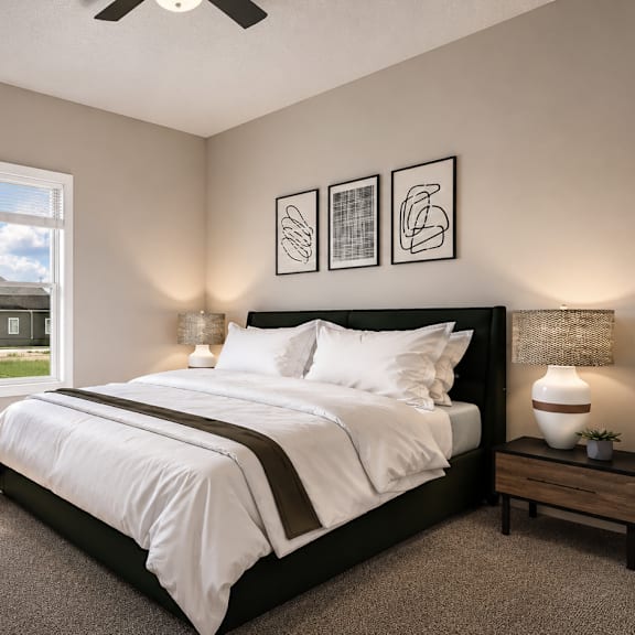 A bedroom with a large bed, a ceiling fan, and pictures on the wall.