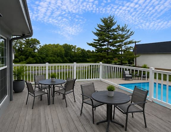 A table and chairs set on a deck overlooking a pool.