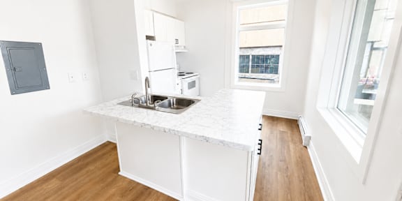 A kitchen with a white fridge and a window.
