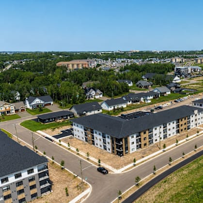 A large, modern building complex with a parking lot in front.
