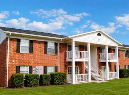 A red brick apartment building with white trim and a white porch.