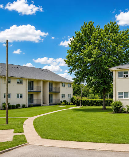 Apartment complex with a green lawn and a clear blue sky.