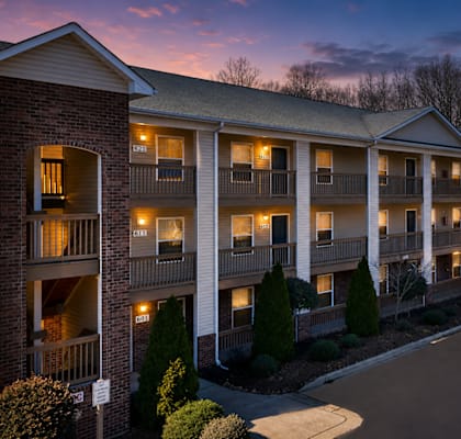 A large apartment complex with multiple balconies and lights on.