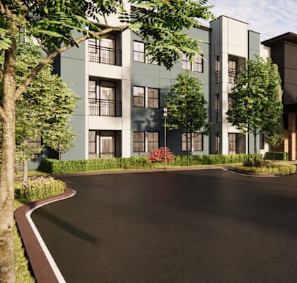 A modern apartment complex with a paved driveway and landscaping.