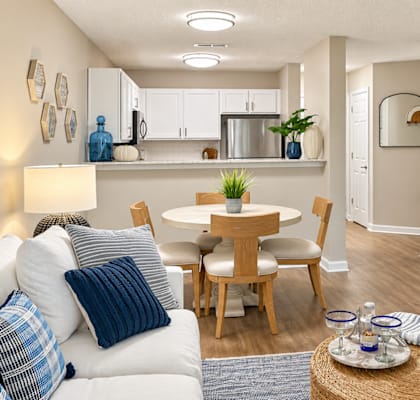 A modern living room with a dining area and kitchen in the background.