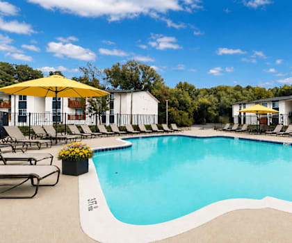 A large outdoor swimming pool surrounded by lounge chairs and umbrellas.