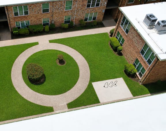 A courtyard with a circular garden and a white square with a black design.