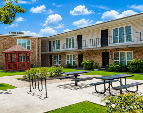 A sunny day at the courtyard of a brick building with a red entrance and a gazebo.