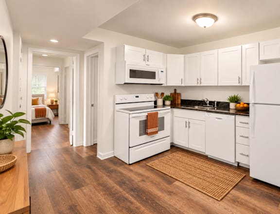 A white kitchen with a refrigerator, oven, and microwave.
